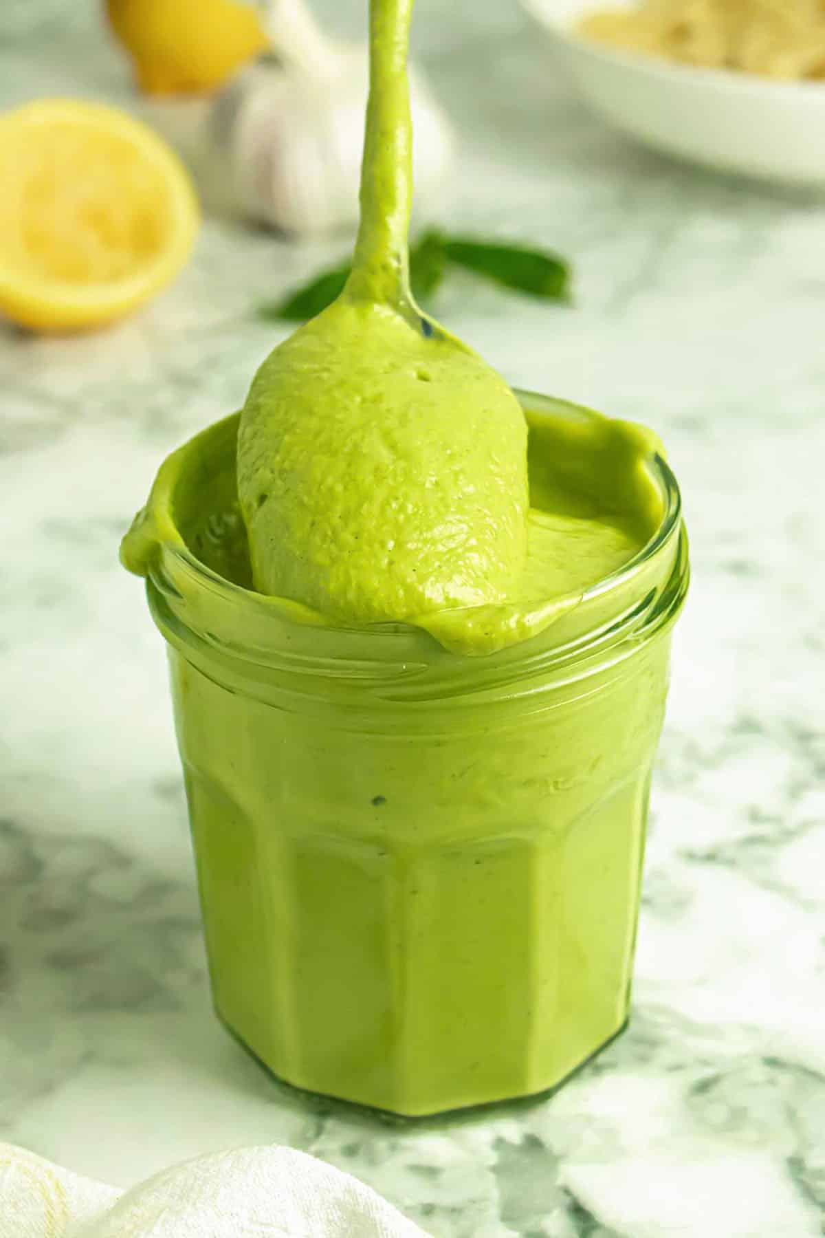 spooning vegan avocado pesto out of a jar