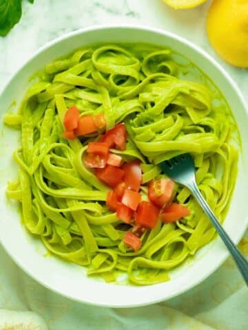 bowl of vegan avocado pasta topped with chopped tomato