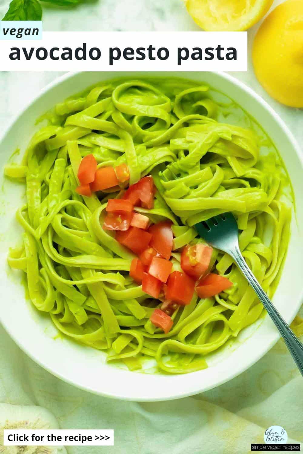 bowl of vegan avocado pasta topped with chopped tomato, text overlay