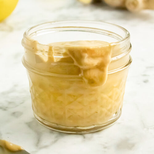 jar of lemon tahini sauce on a marble table, text overlay