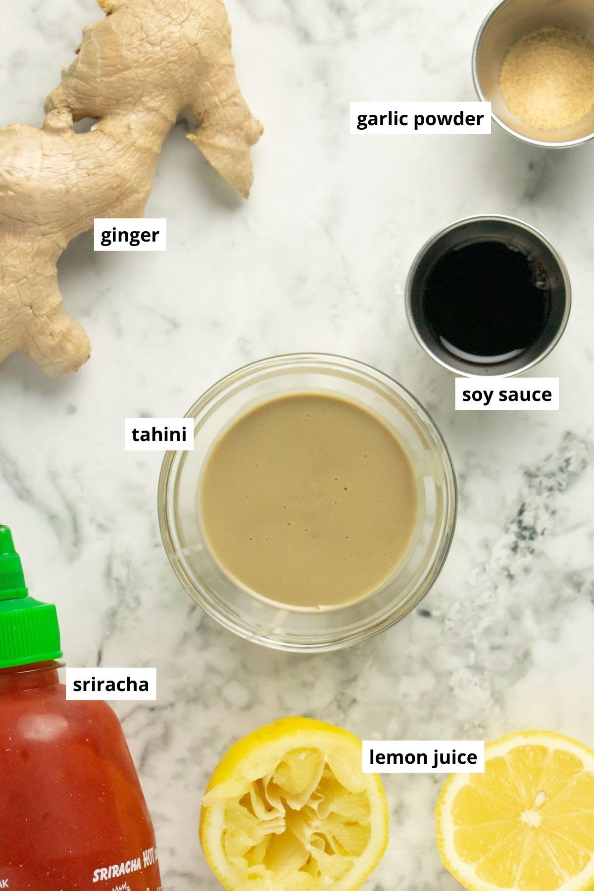 tahini, lemon, and other seasonings in cups on a marble table