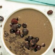 chocolate smoothie bowl topped with frozen cherries and chocolate chips