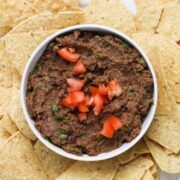 vegan black bean dip in a bowl surrounded by tortilla chips