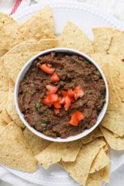 vegan black bean dip in a bowl surrounded by tortilla chips