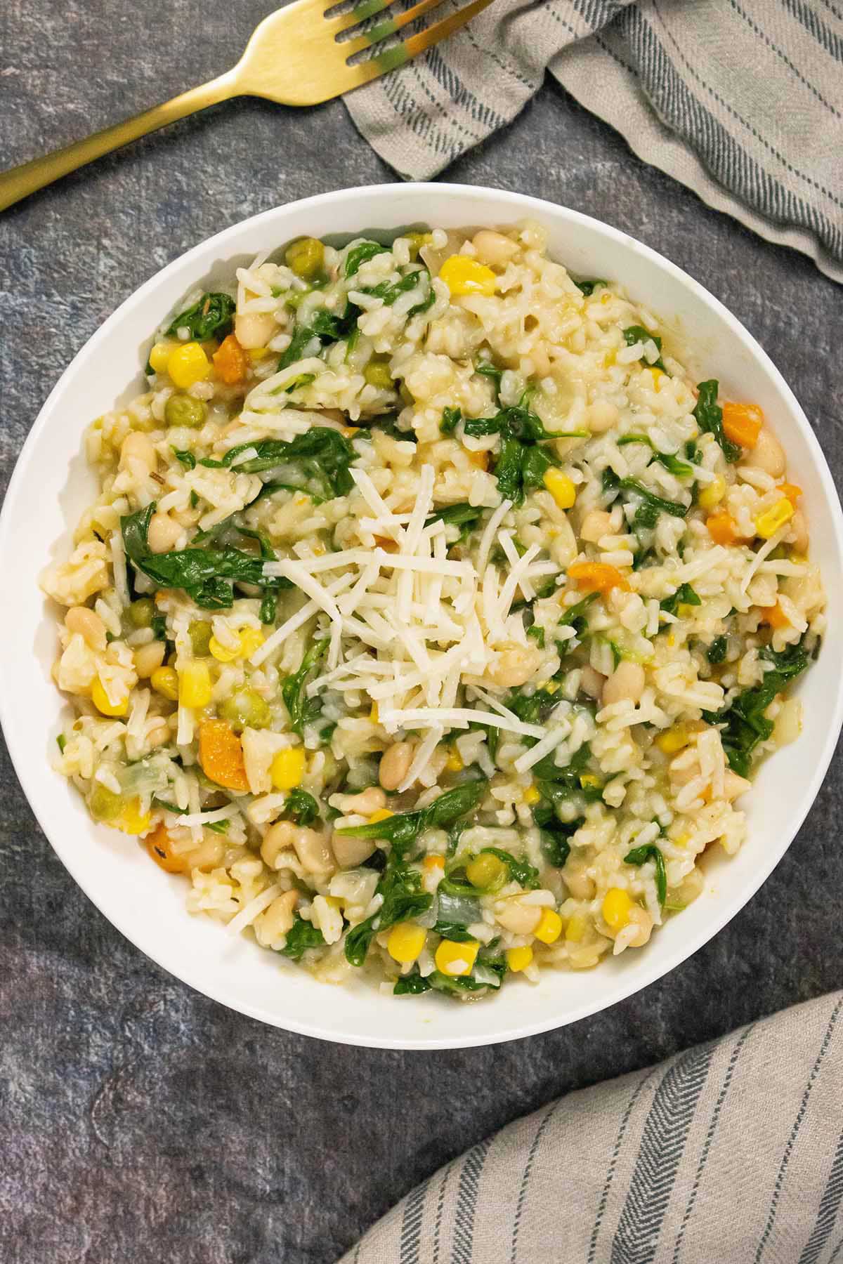 vegan Instant Pot risotto in a white bowl topped with white cheese shreds