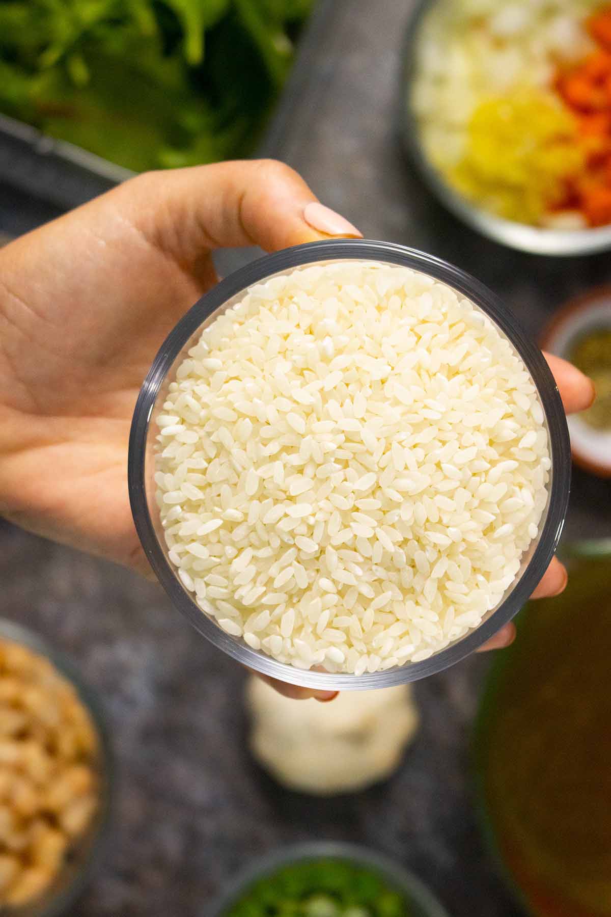 hand holding a glass bowl of arborio rice