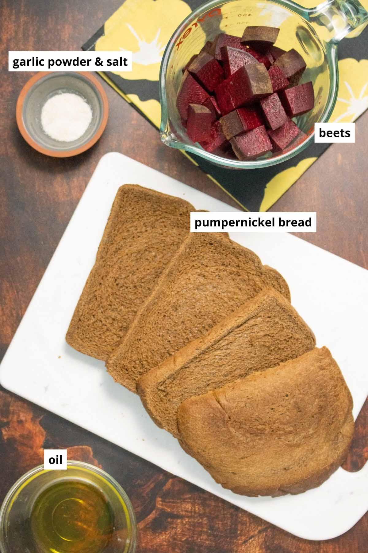 pumpernickel bread, beets, oil, and garlic salt on a wooden table