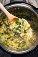 wooden spoon full of vegan risotto over an Instant Pot