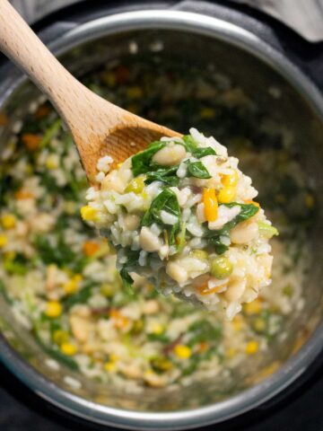 wooden spoon full of risotto over an Instant Pot