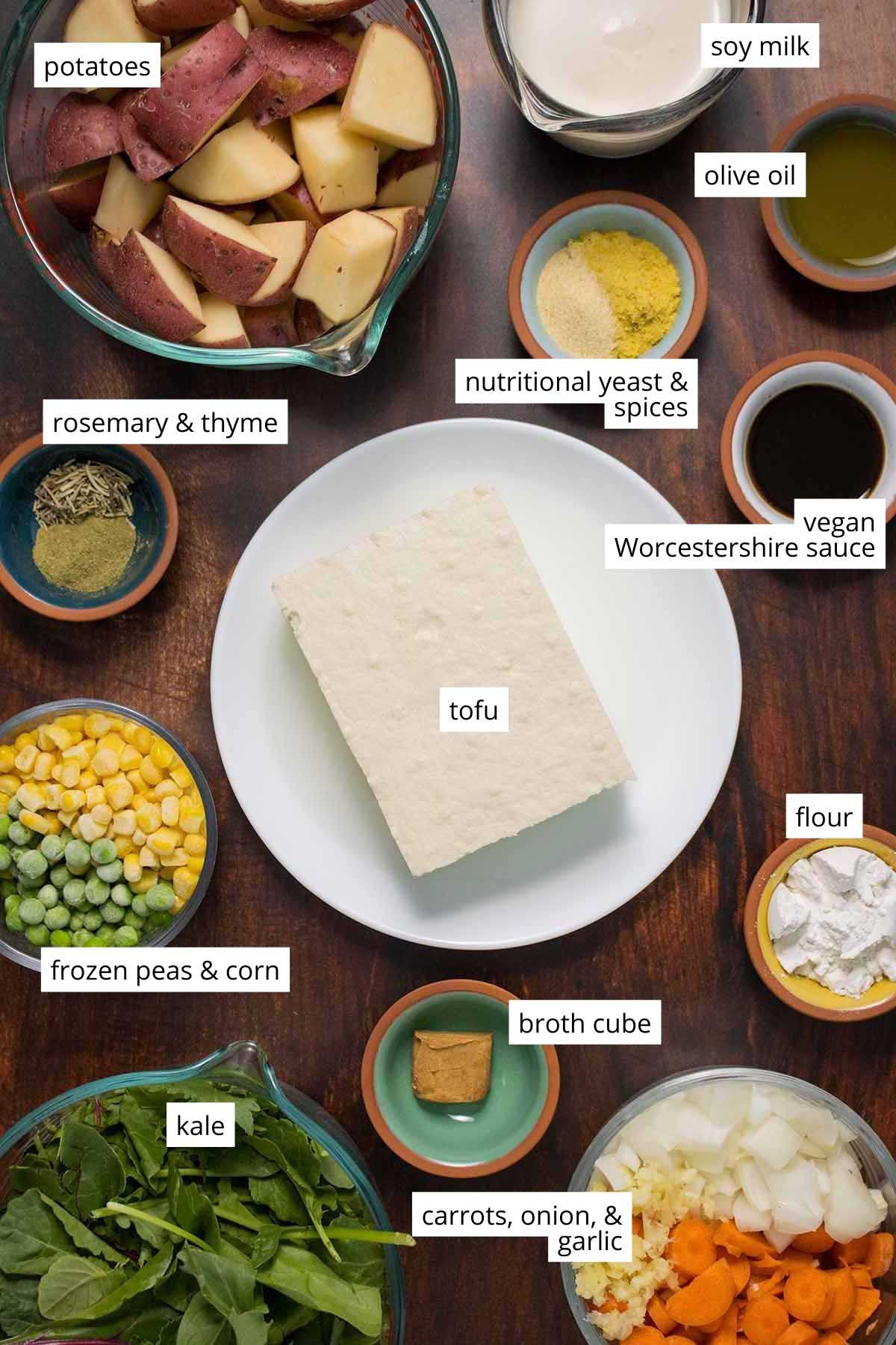 tofu, veggies, and seasonings in bowls on a wooden table, text labels on each ingredient
