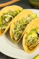 vegan tacos on a white plate with cabbage, avocado, and chimichurri sauce