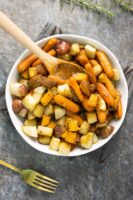 white serving bowl of maple roasted root vegetables with a wooden serving spoon
