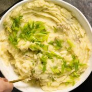 olive oil mashed potatoes in a serving bowl topped with green onion pieces