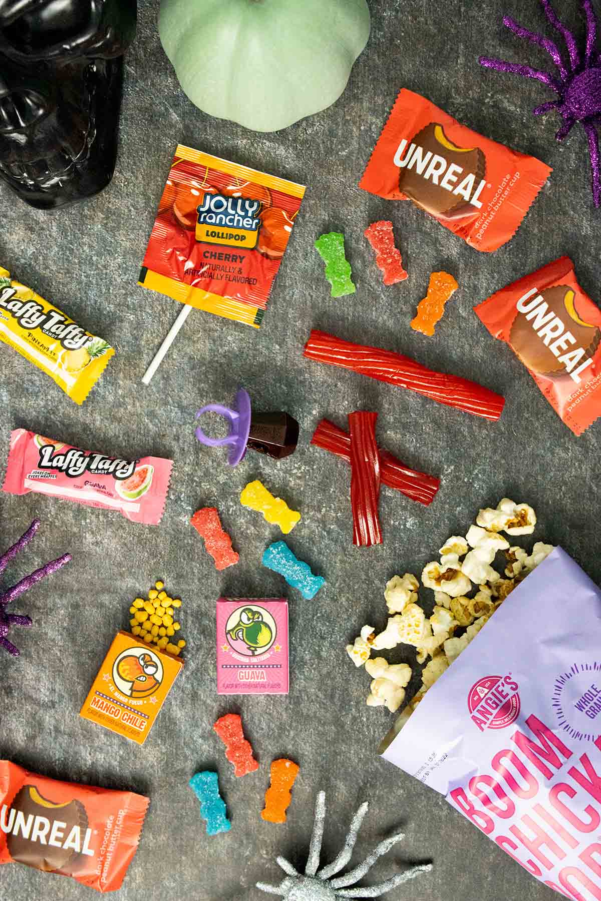 an assortment of vegan Halloween candy on a slate counter with glitter spiders