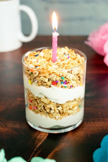 birthday cake granola parfait with yogurt in a glass. It has a candle on top!
