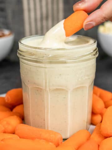 hand dipping a carrot into cashew ranch dressing