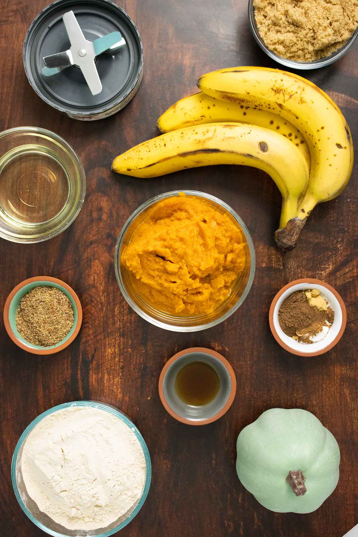 pumpkin puree, bananas, flour, and spices on a wooden countertop