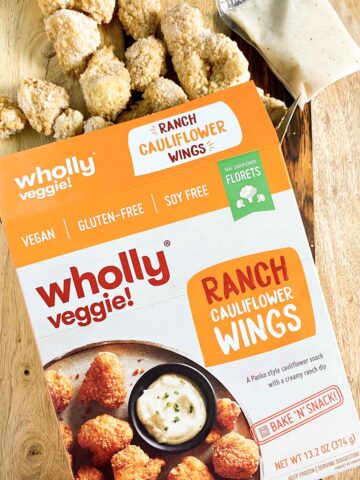 box of Wholly Veggie! Ranch Cauliflower Wings with the frozen wings spilling out onto a wooden table