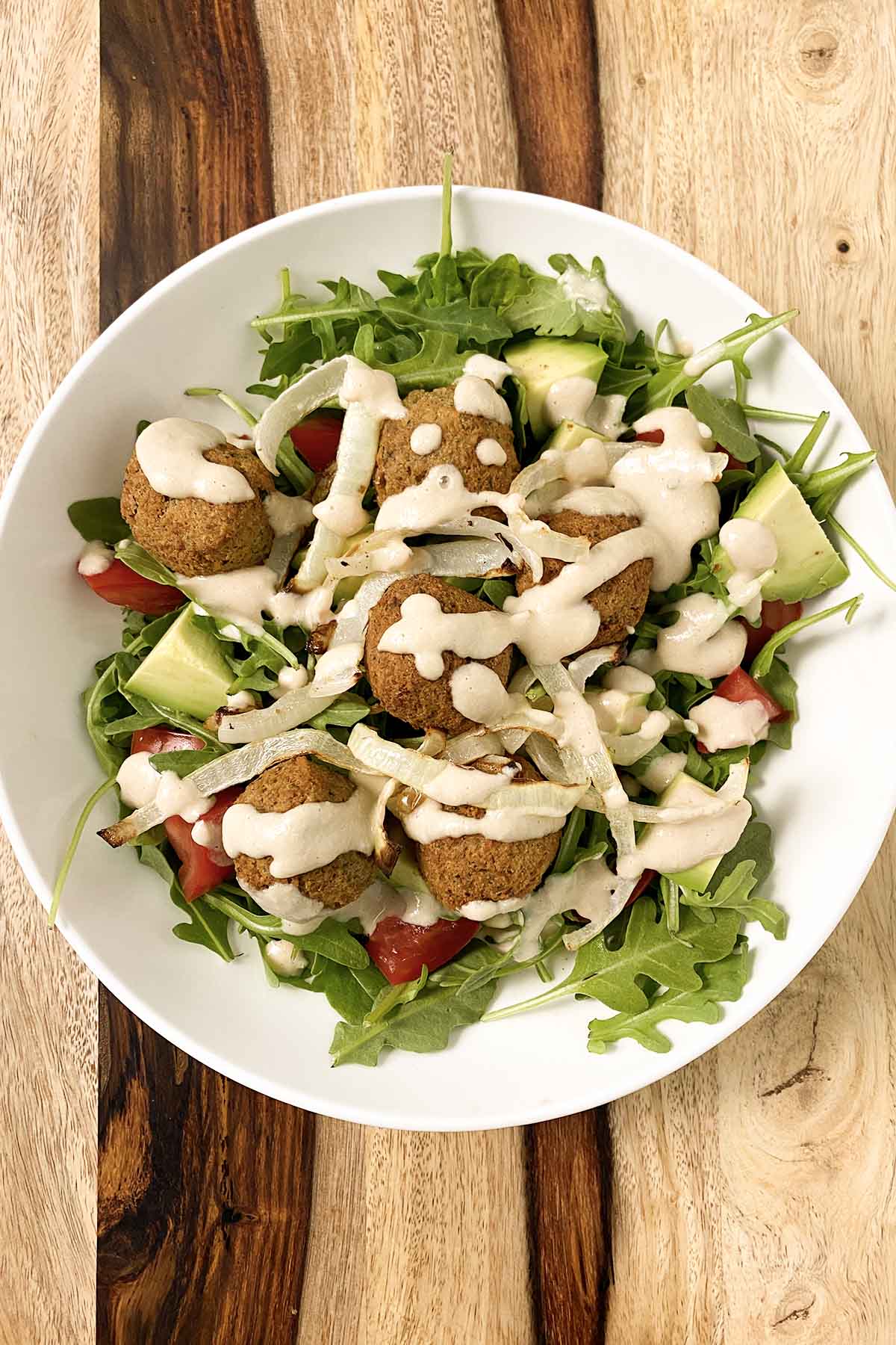 vegan falafel salad with a creamy dressing in a white bowl