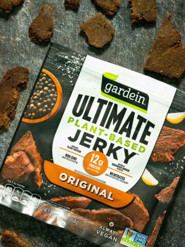 bag of Gardein Ultimate Plant Based Jerky on a slate table surrounded by big pieces of the jerky