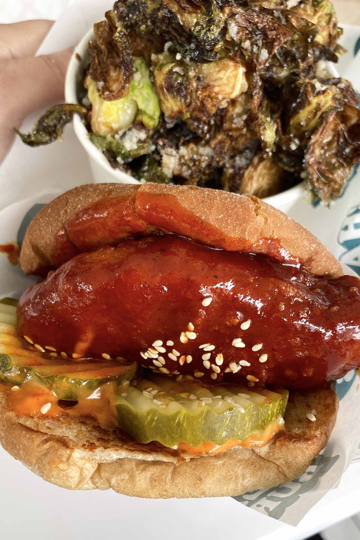 vegan Korean BBQ chicken sandwich with a side of Brussels sprouts on a tray
