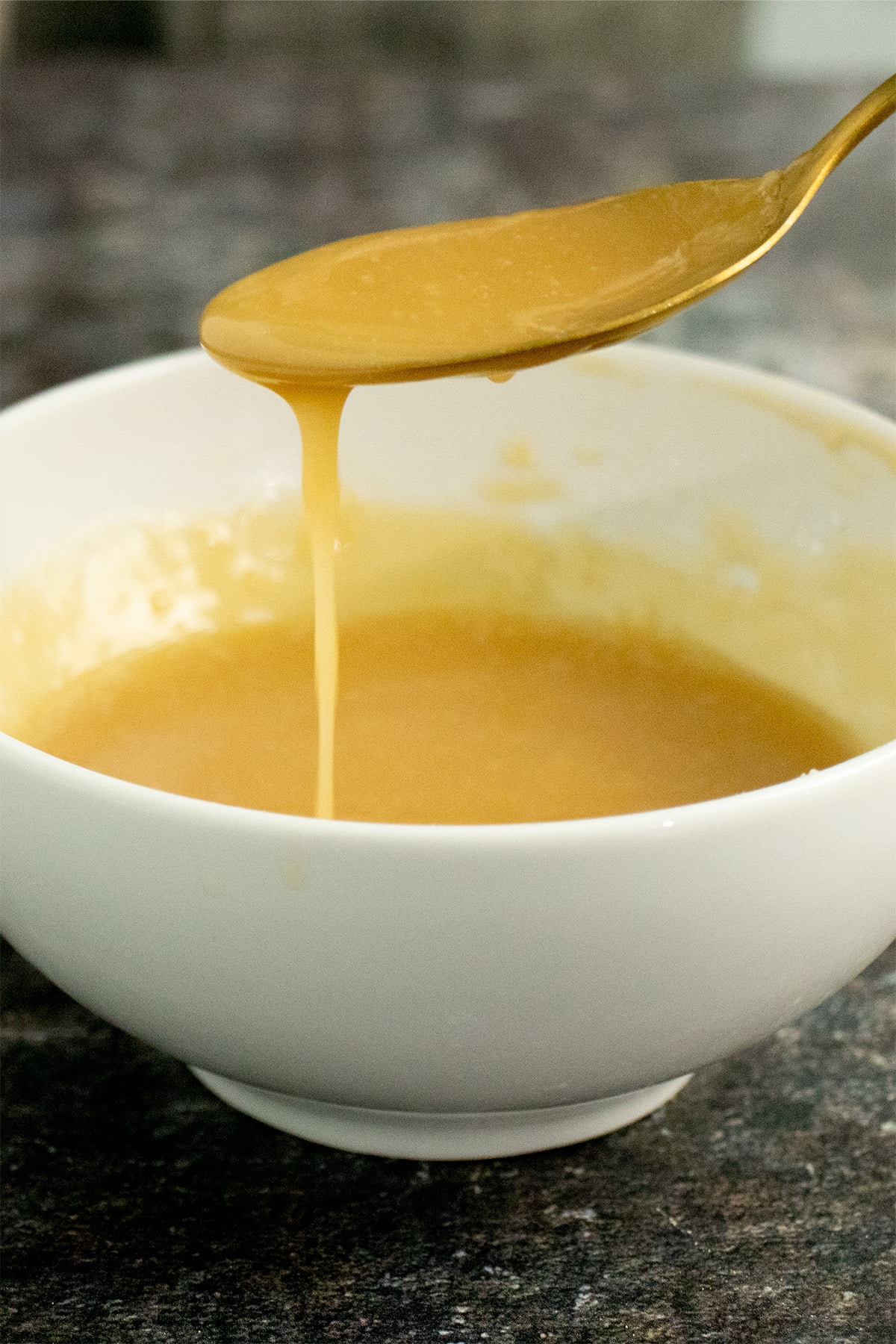 maple glaze drizzling off of a spoon into a white bowl