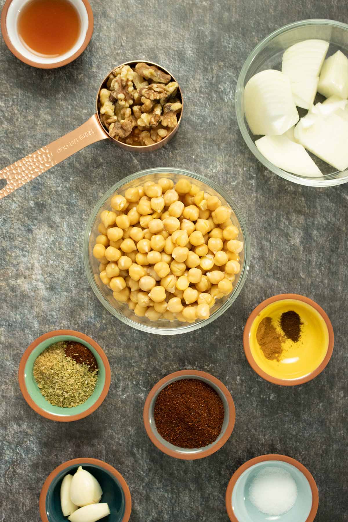 chickpeas, walnuts, and spices in bowls on a slate table