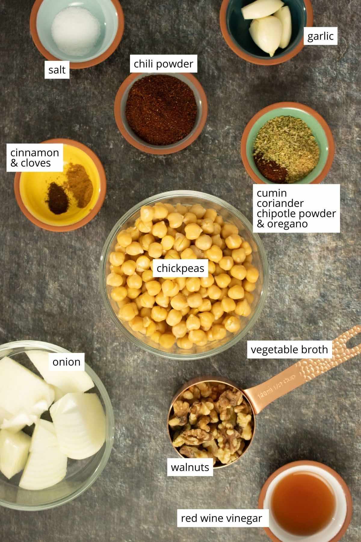 walnuts, chickpeas, and spices arranged in bowls on a table with text labels on each ingredient