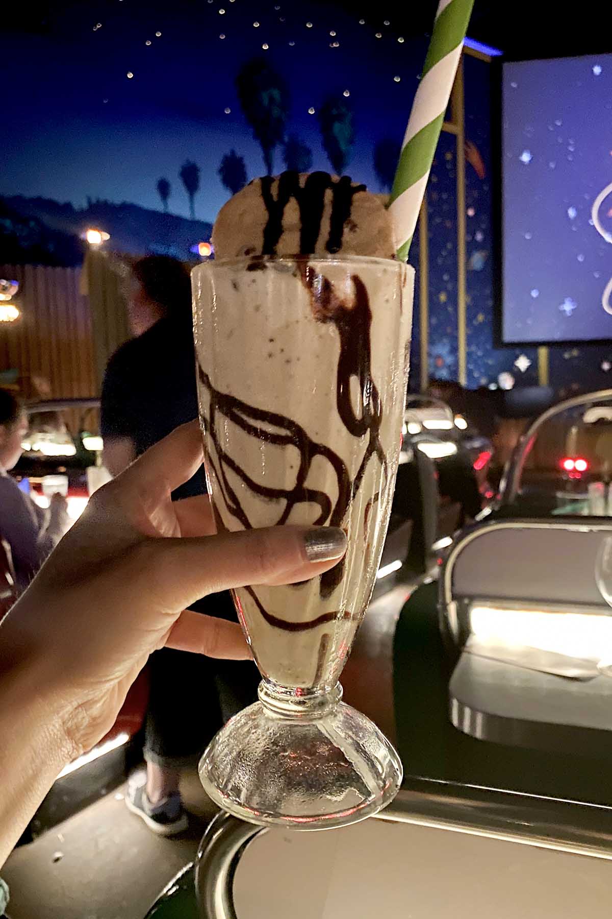 hand holding a vegan shake with a whole cookie on top