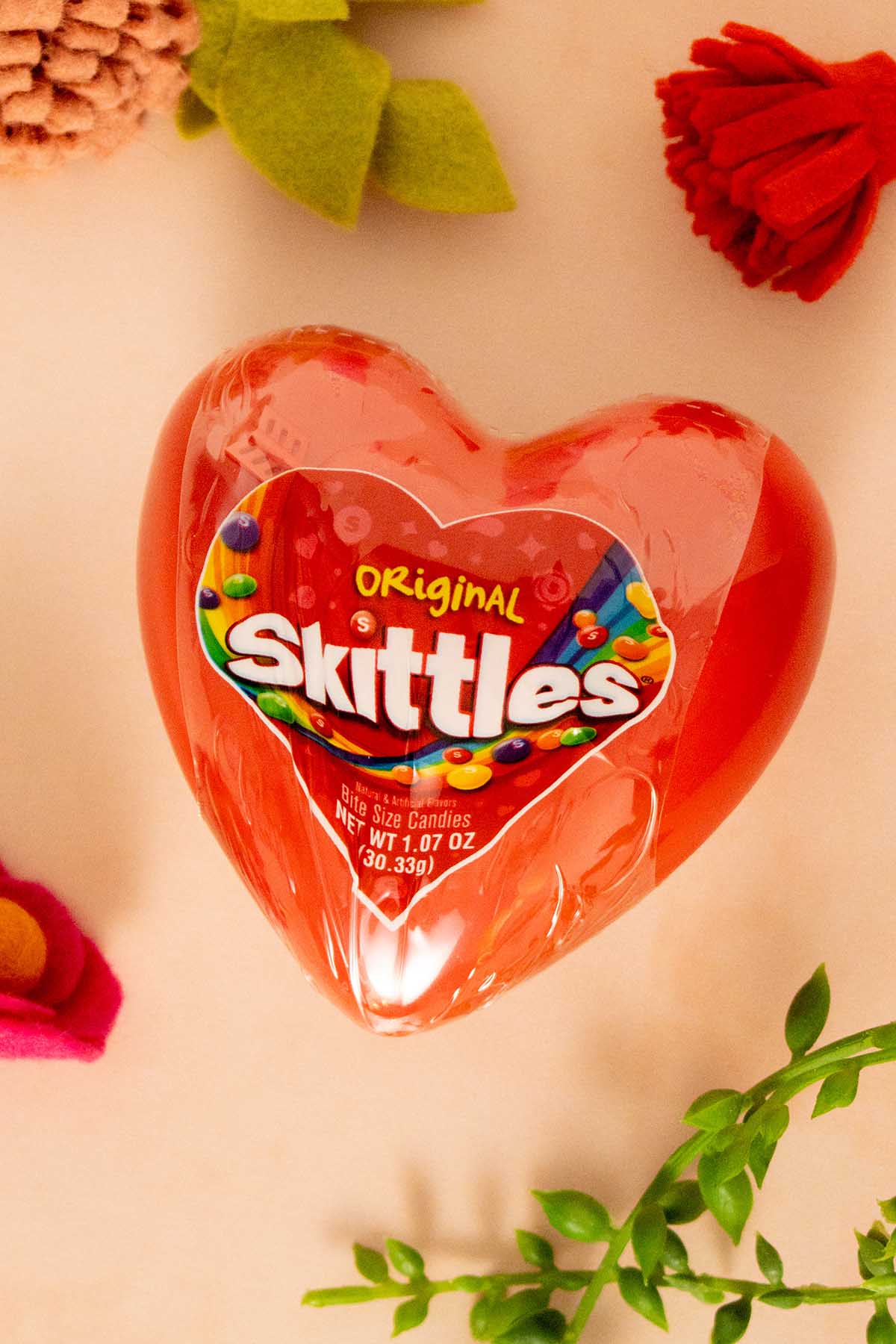 heart-shaped box of Skittles surrounded by flowers
