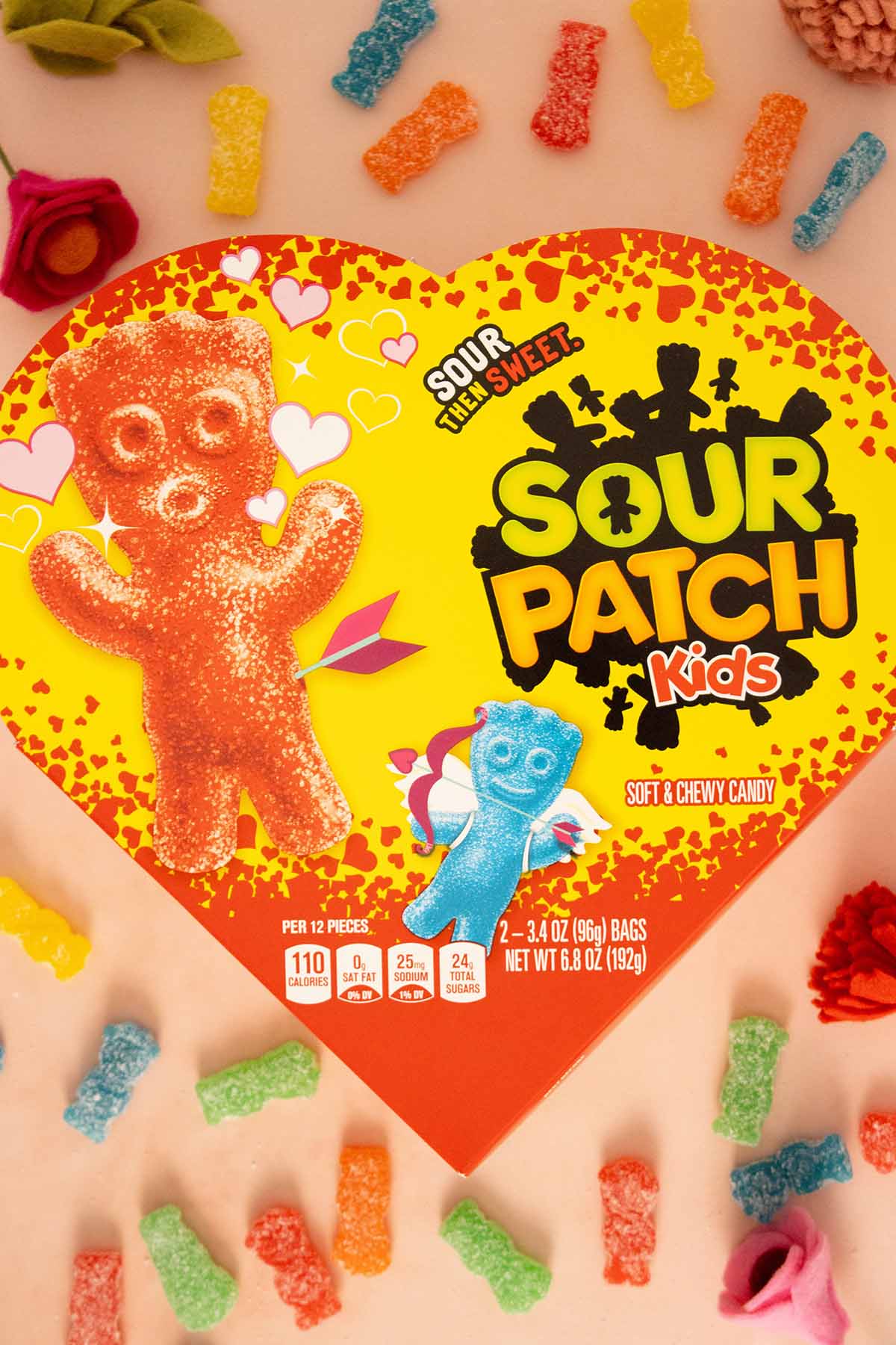 heart-shaped box of Sour Patch Kids surrounded by candy