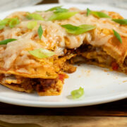 stacked enchiladas on a plate with a bite taken out, so you can see the filling