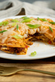 stacked enchiladas on a plate with a bite taken out, so you can see the filling