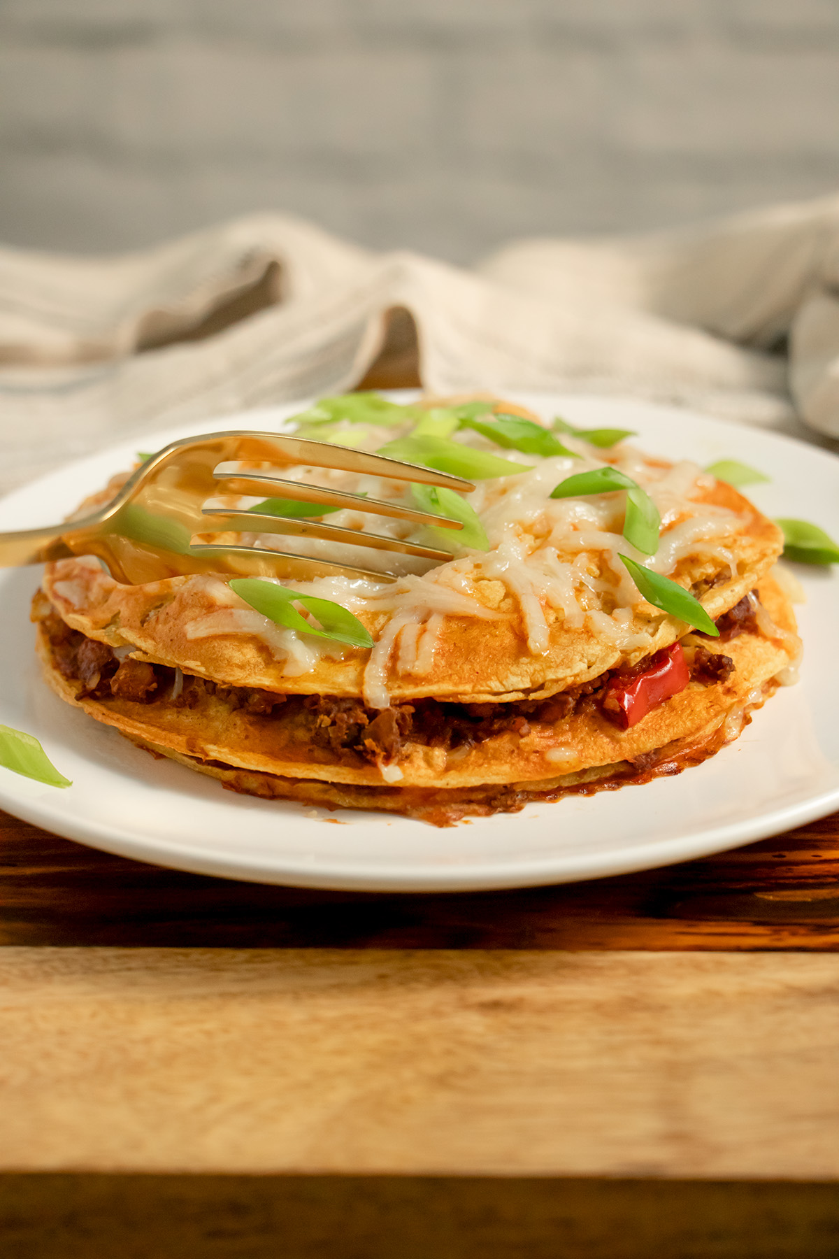 stacked enchiladas on a plate with a fork