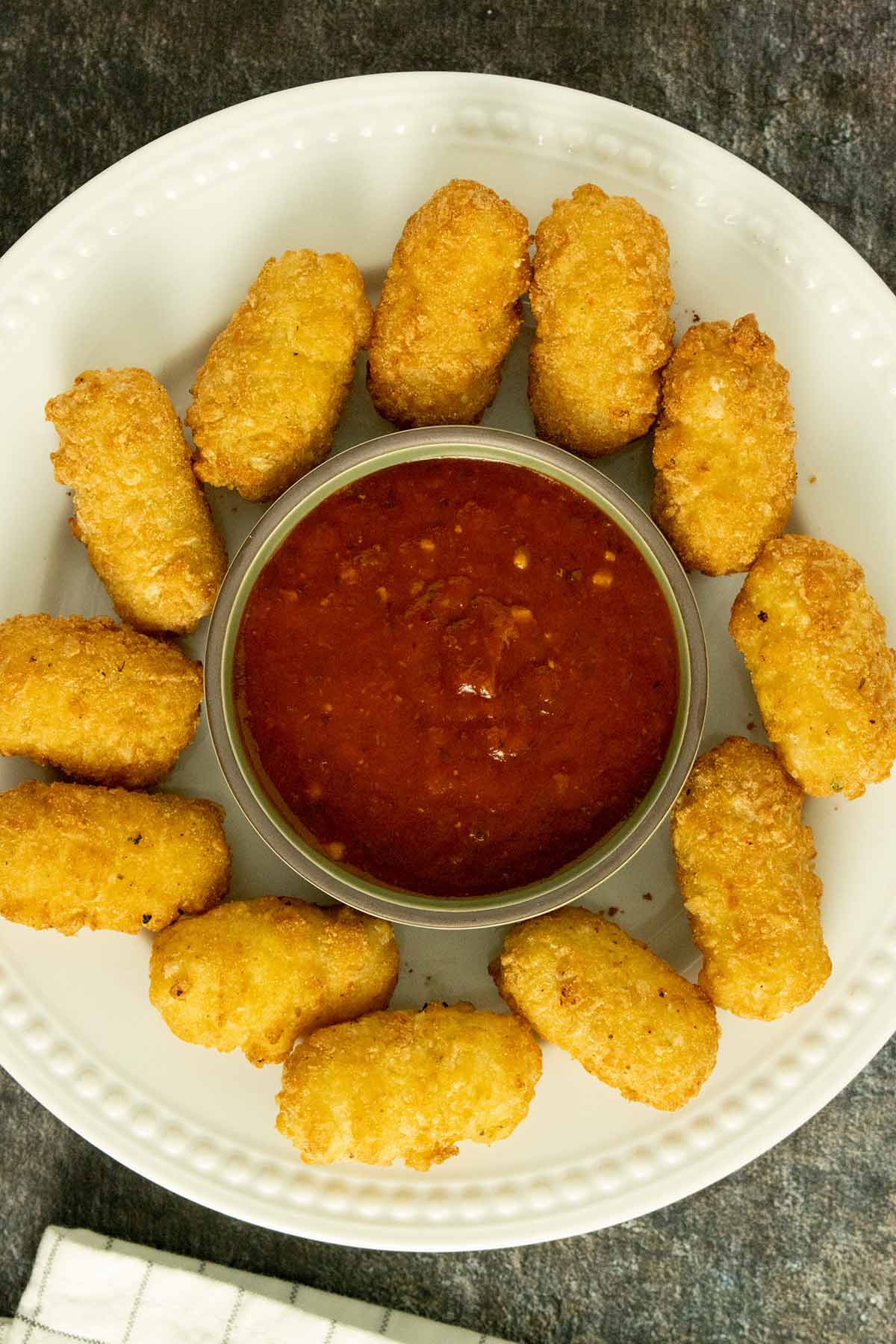 Wholly Veggie! Mozzarella Sticks on a white plate with a ramekin of sauce in the middle