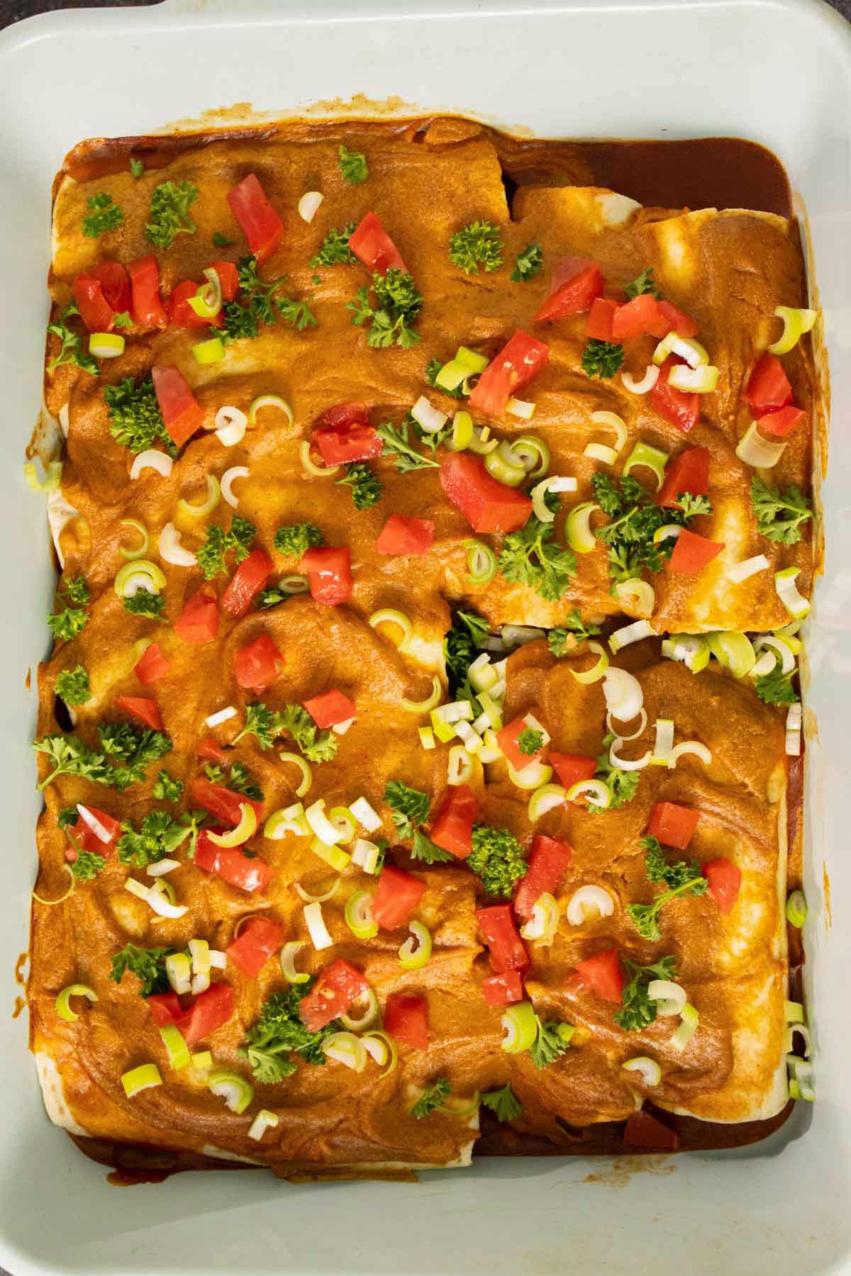 black bean sweet potato enchiladas in the pan after baking and adding toppings