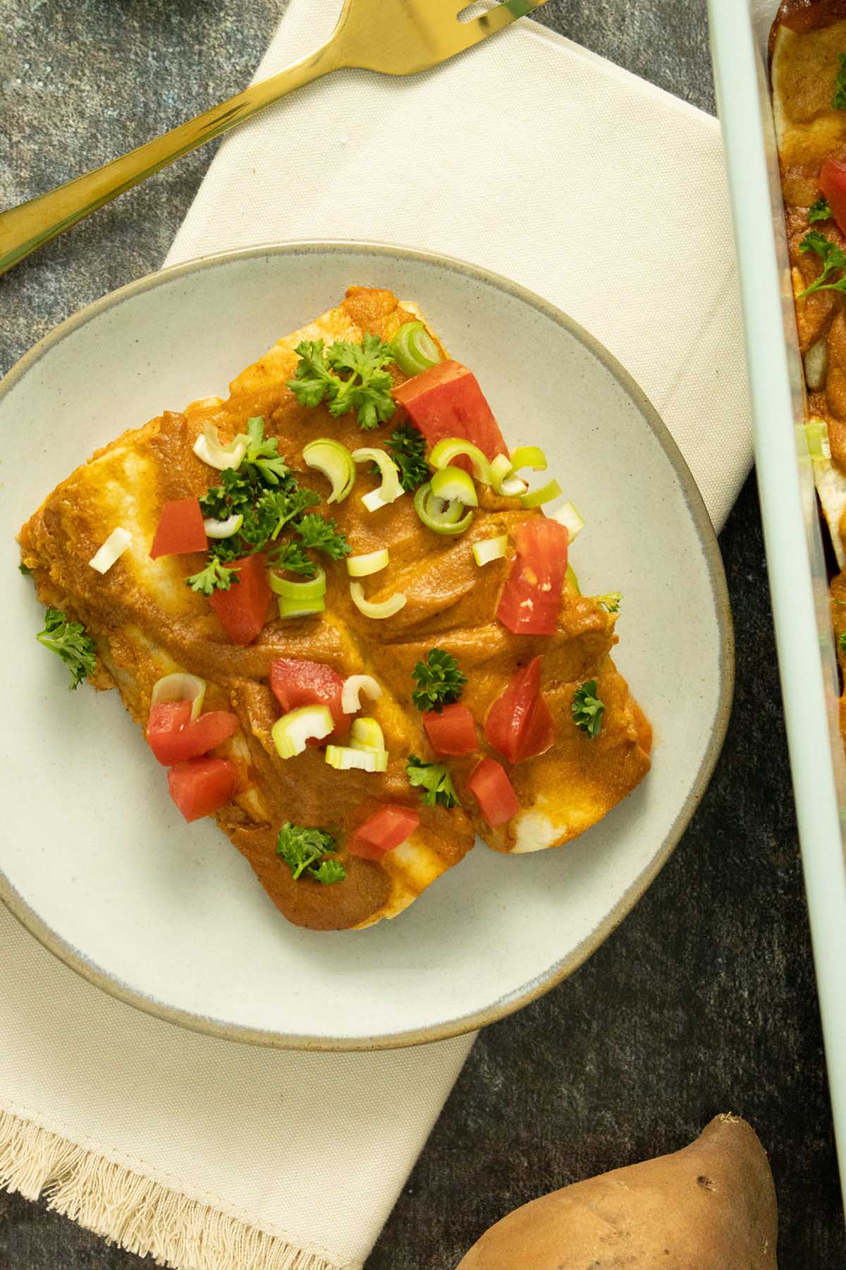 two rolled up enchiladas on a plate next to the baking pan