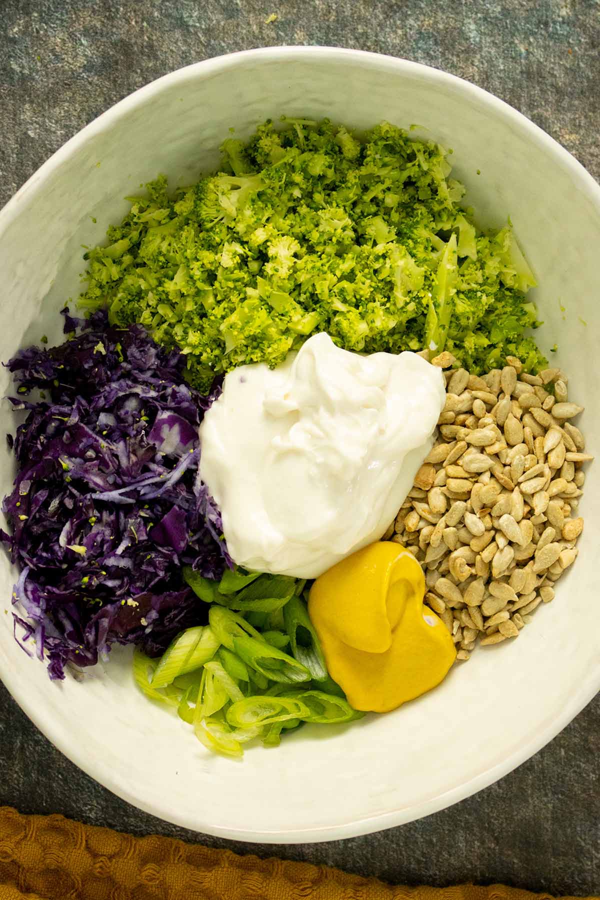 broccoli slaw ingredients in a bowl, ready to mix