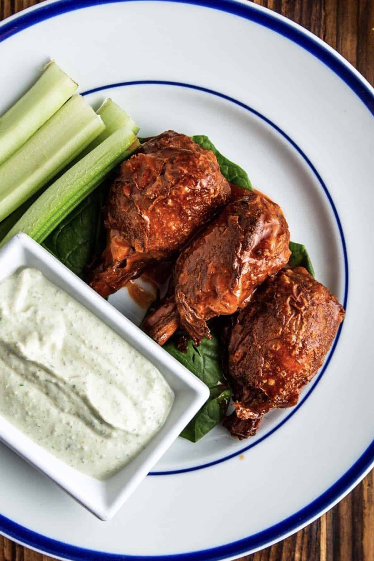 vegan buffalo lollipops on a white plate with celery and vegan blue cheese
