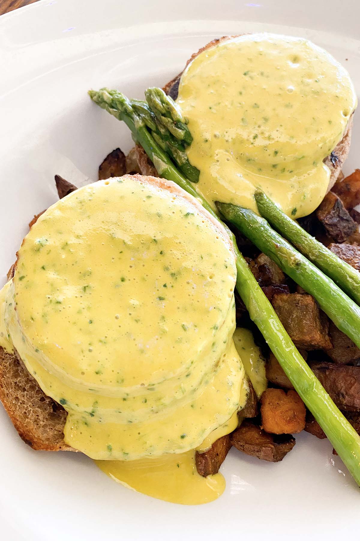 Cafe Sunflower tofu Benedict with asparagus and potatoes in a white, shallow bowl