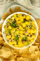 tray of chips with a bowl of mango salsa