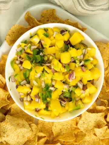 tray of chips with a bowl of mango salsa
