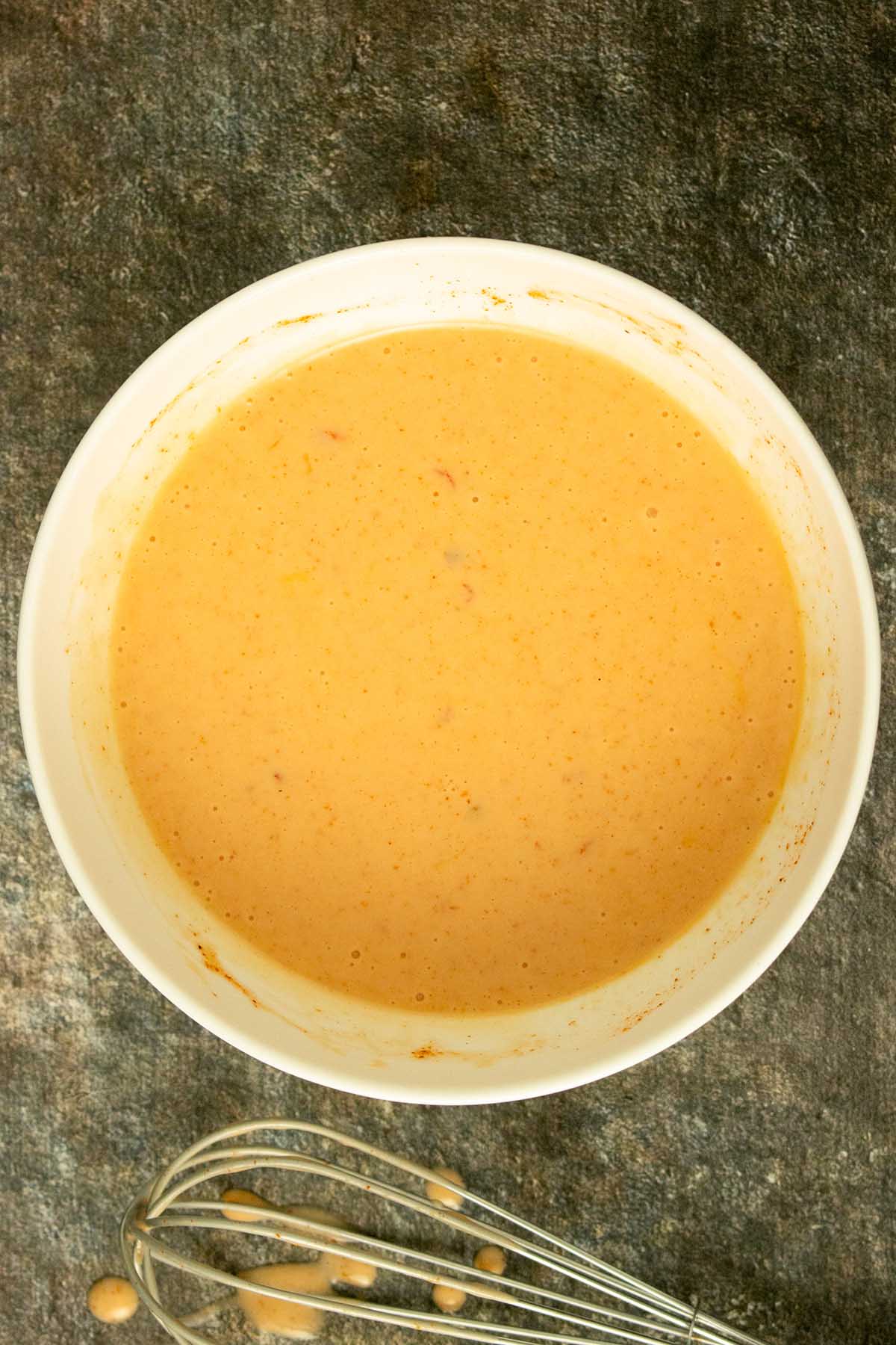 white bowl of creamy vegan bang bang sauce on a slate table