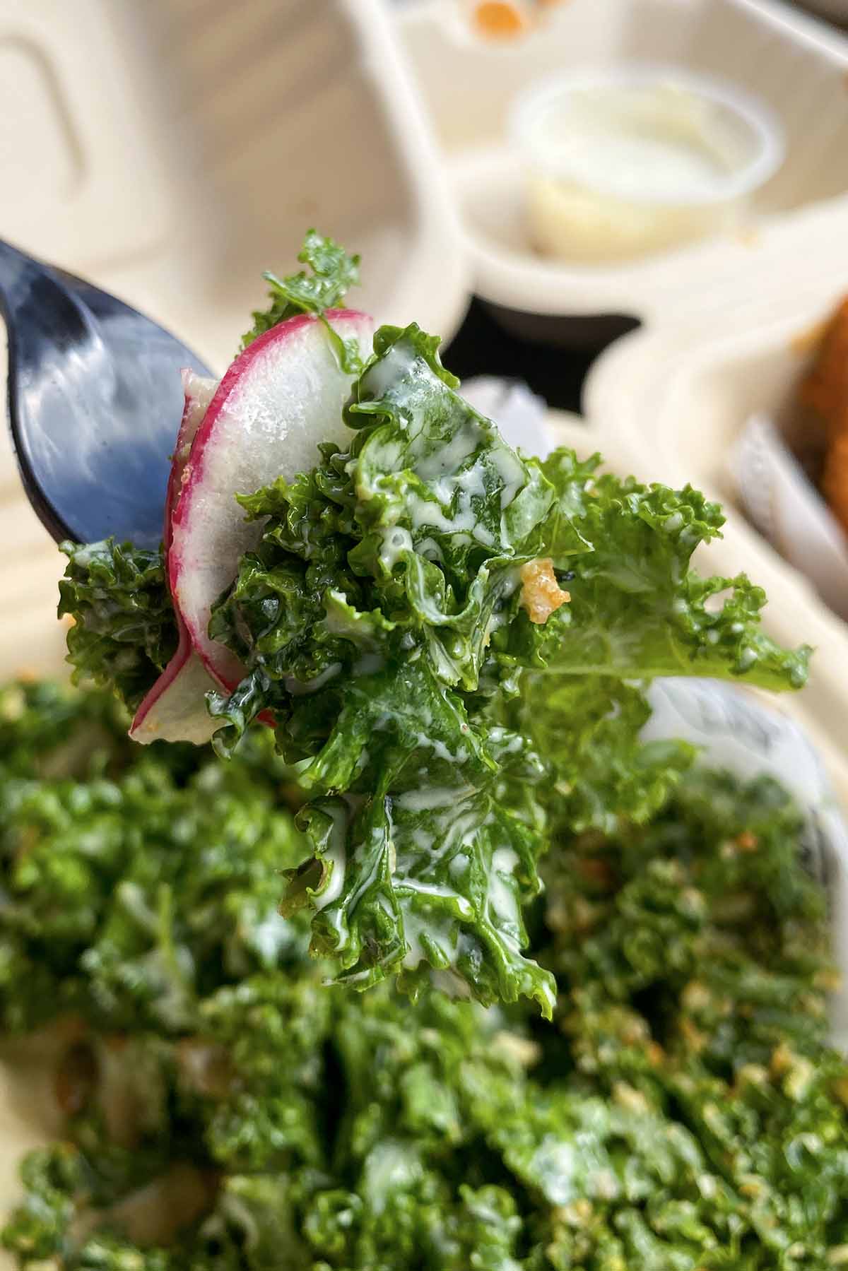 fork with a bite of kale caesar salad on it