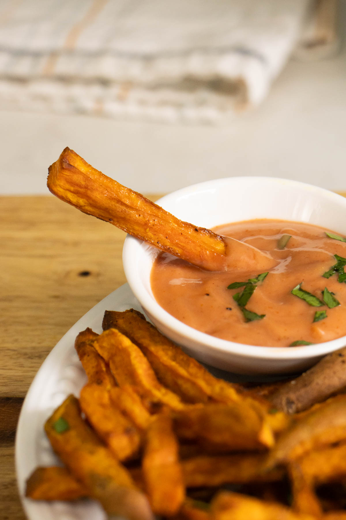close-up of a sweet potato fry dipped in the sauce