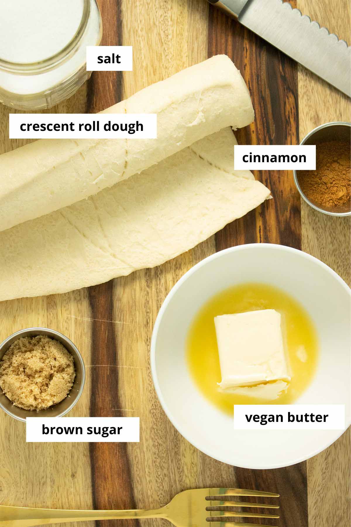 vegan cinnamon roll ingredients on a wooden cutting board with text labeling each one