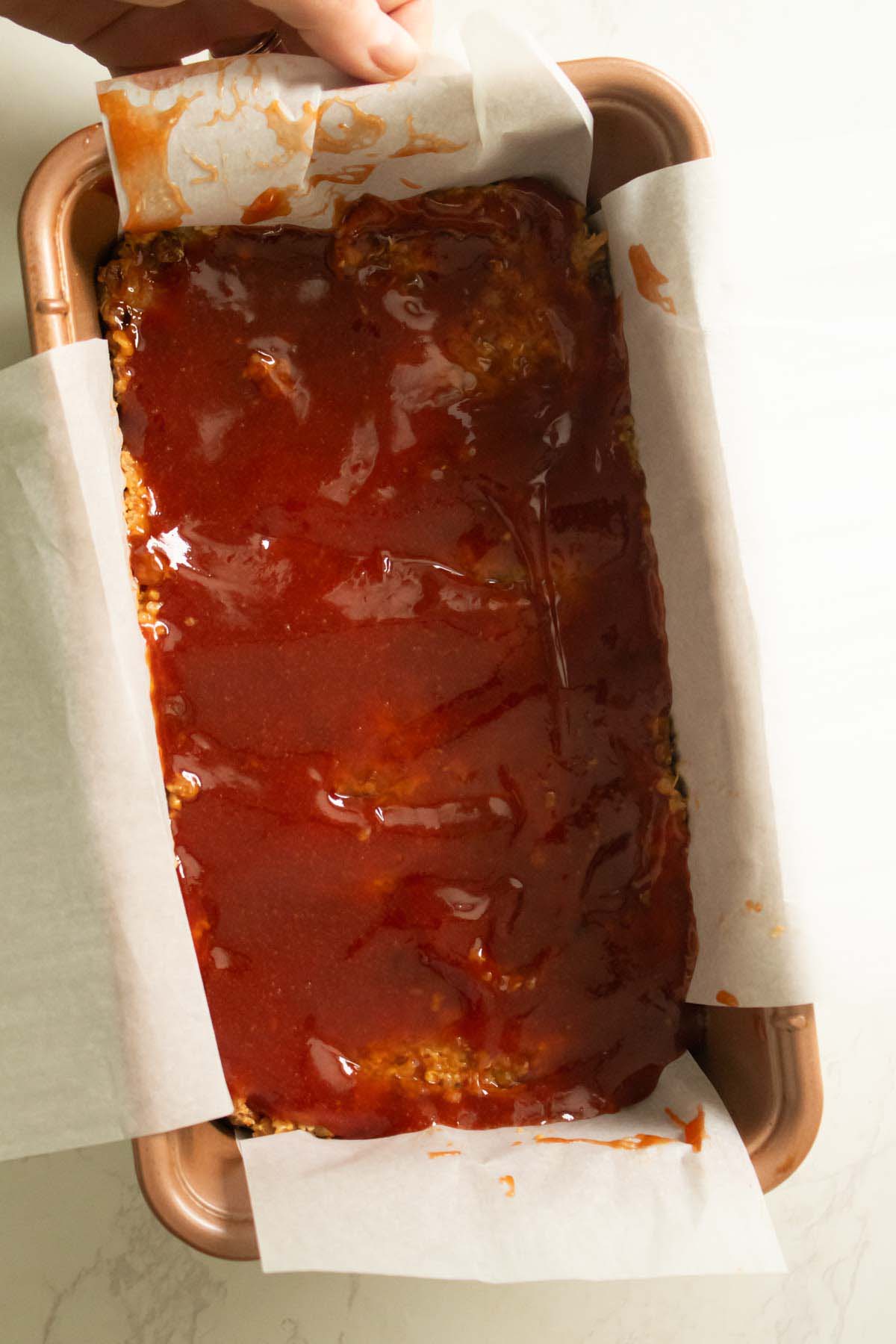 quinoa lentil meatloaf mixture with the glaze spread on, before baking