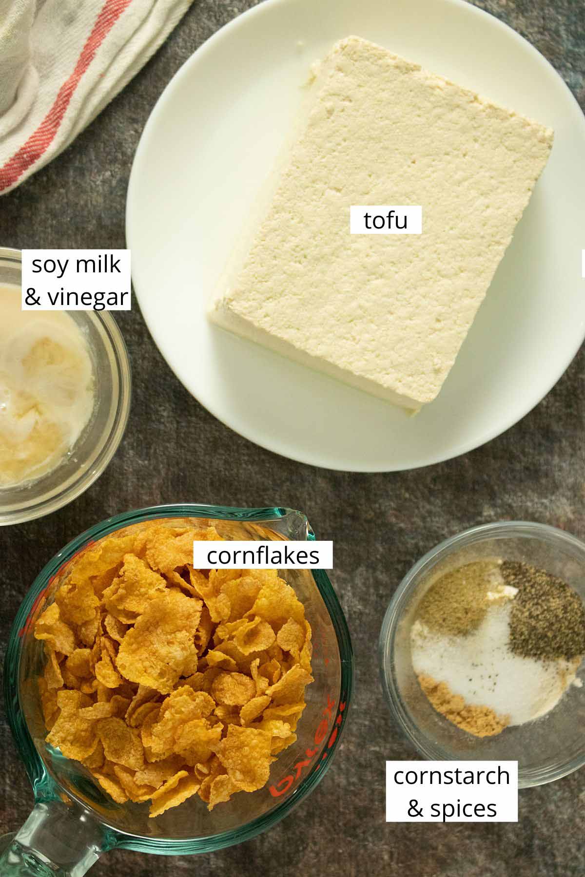tofu, cornflakes, vegan buttermilk, and a bowl of spices on a slate table