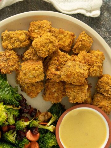 cornflake tofu nuggets on a plate with a salad and a side of dipping sauce