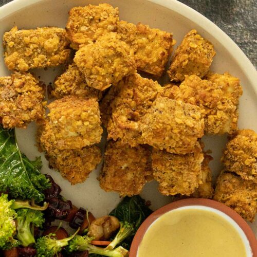 cornflake tofu nuggets on a plate with a salad and a side of dipping sauce